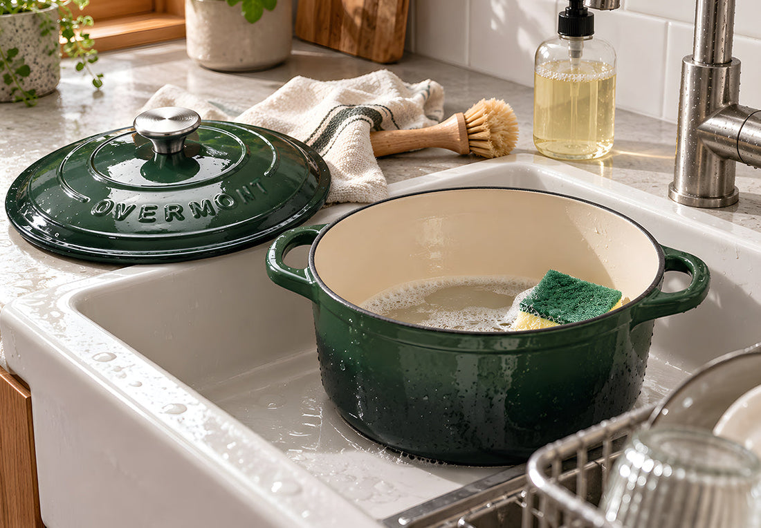 Green Overmont enameled Dutch oven being washed in a sunlit kitchen sink.