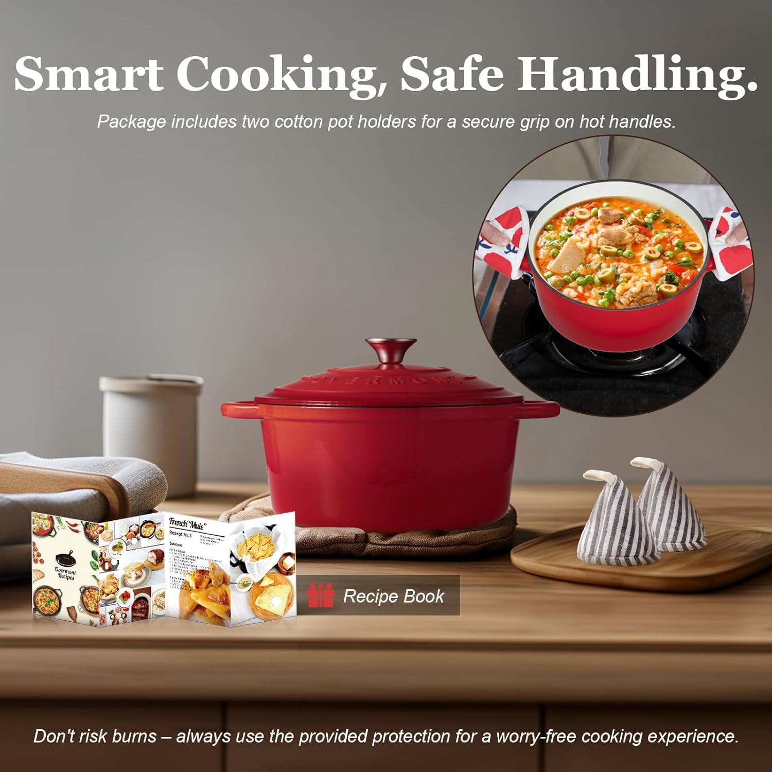 Red cast iron pot with accessories on a wooden surface, including a recipe book and pot holders.